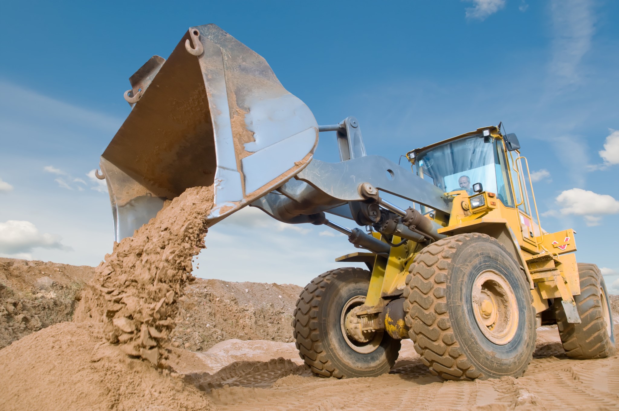 Wheel loader machine unloading sand at eathmoving works in construction site